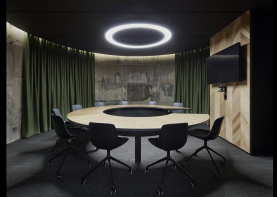 a round table with chairs in a room with green curtains