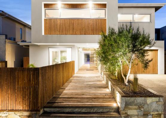 a house with a wooden walkway and a tree