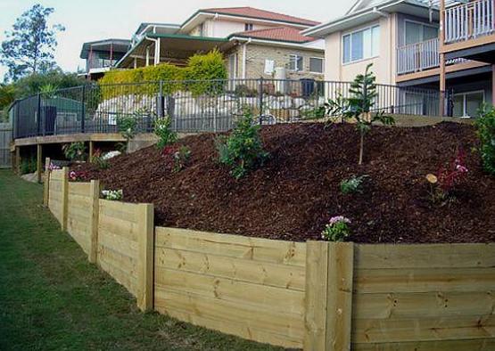 a wooden fenced hillside with plants and a fenced yard
