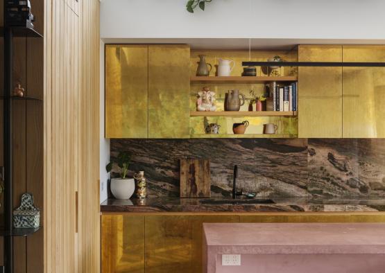 a kitchen with gold cabinets and a pink countertop