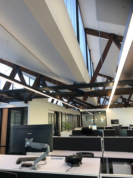 Exposed timber roof trusses against a white office ceiling