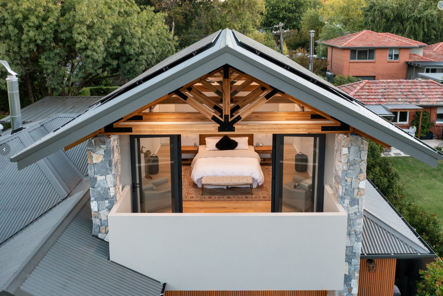 Exposed timber roof trusses on second level of a home looking into a bedroom