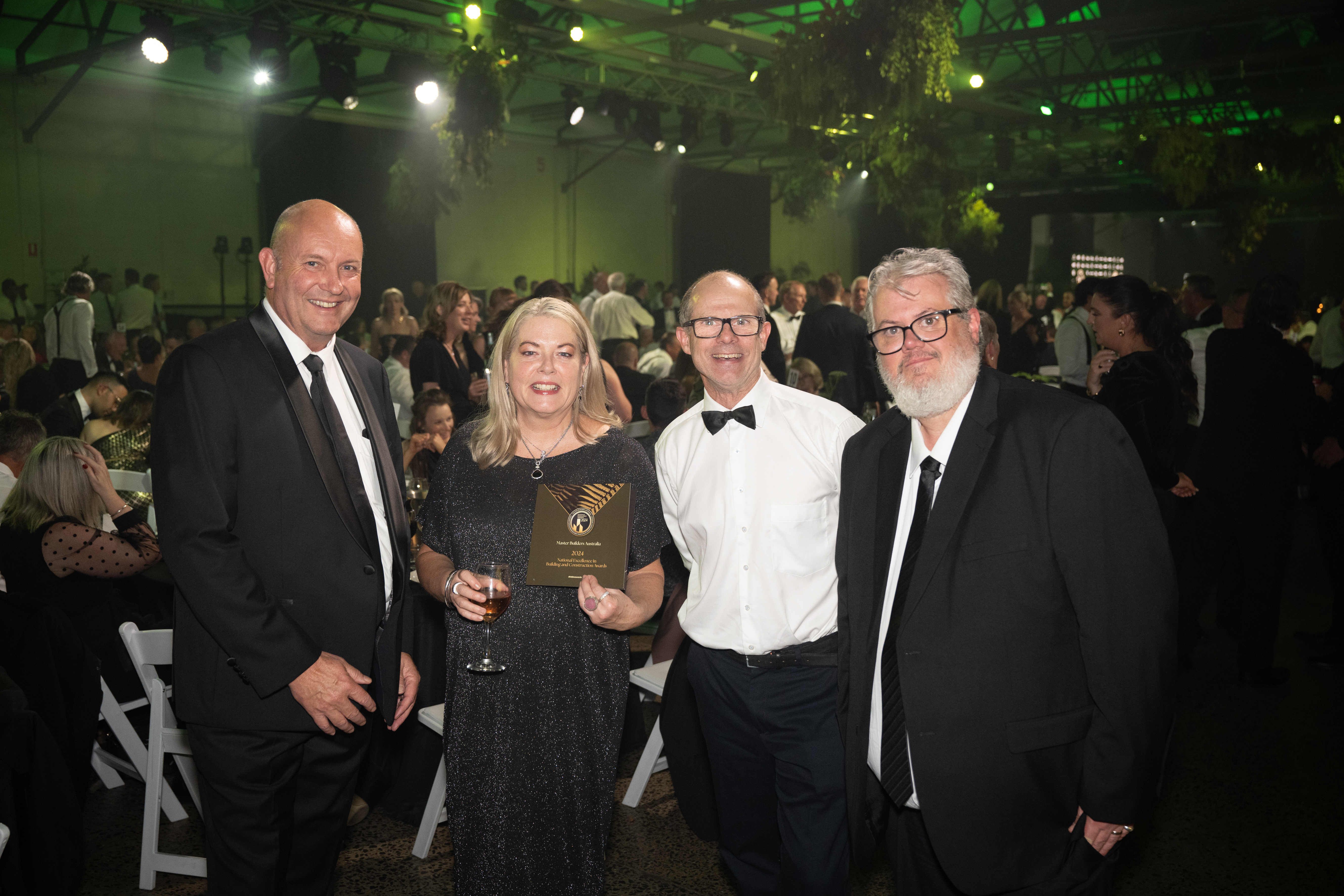 Four people in formal attire celebrating at the Master Builders National Awards.