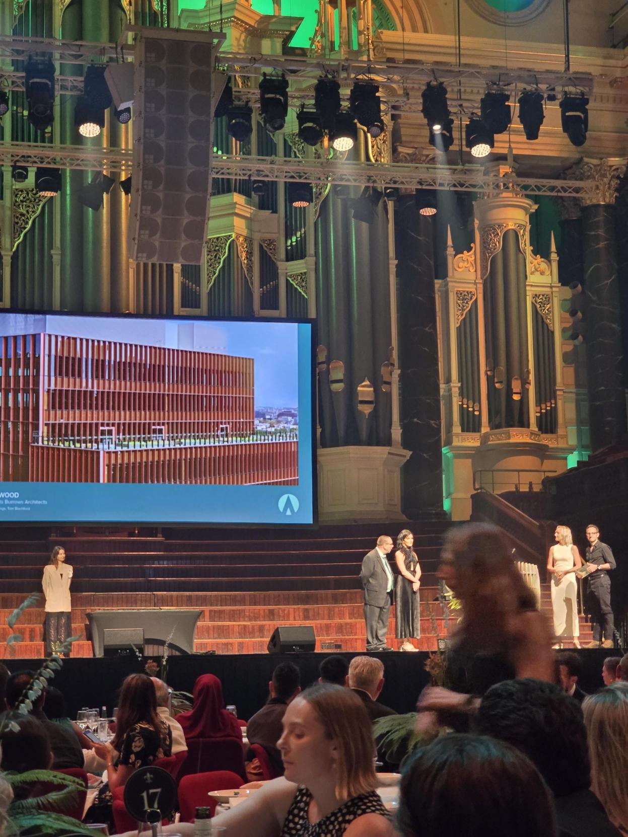 Image of the team behind designing a winning building being presented and award on stage