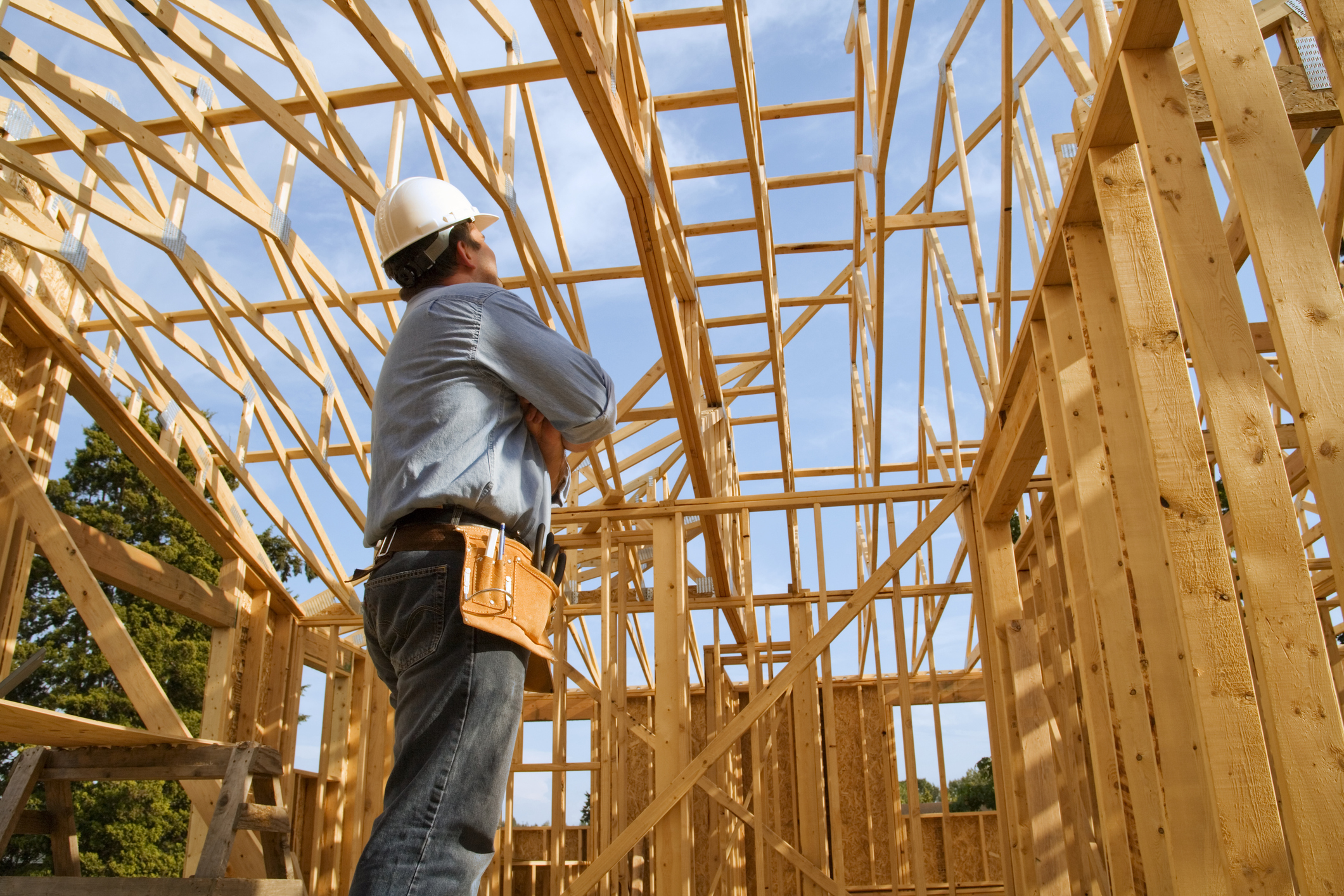 Builder in PPE looking up at timber frame