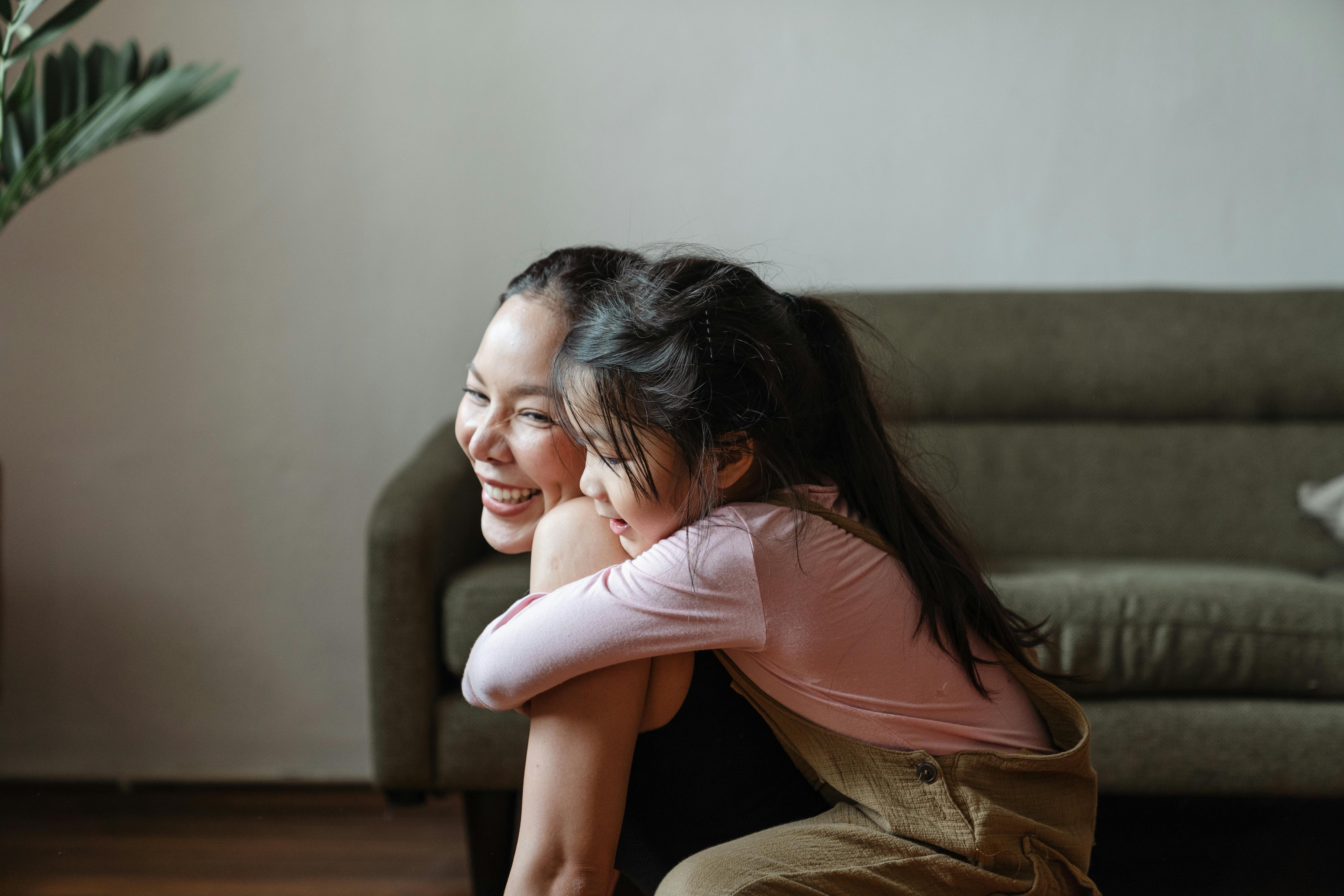 Young daughter hugging mum in living room