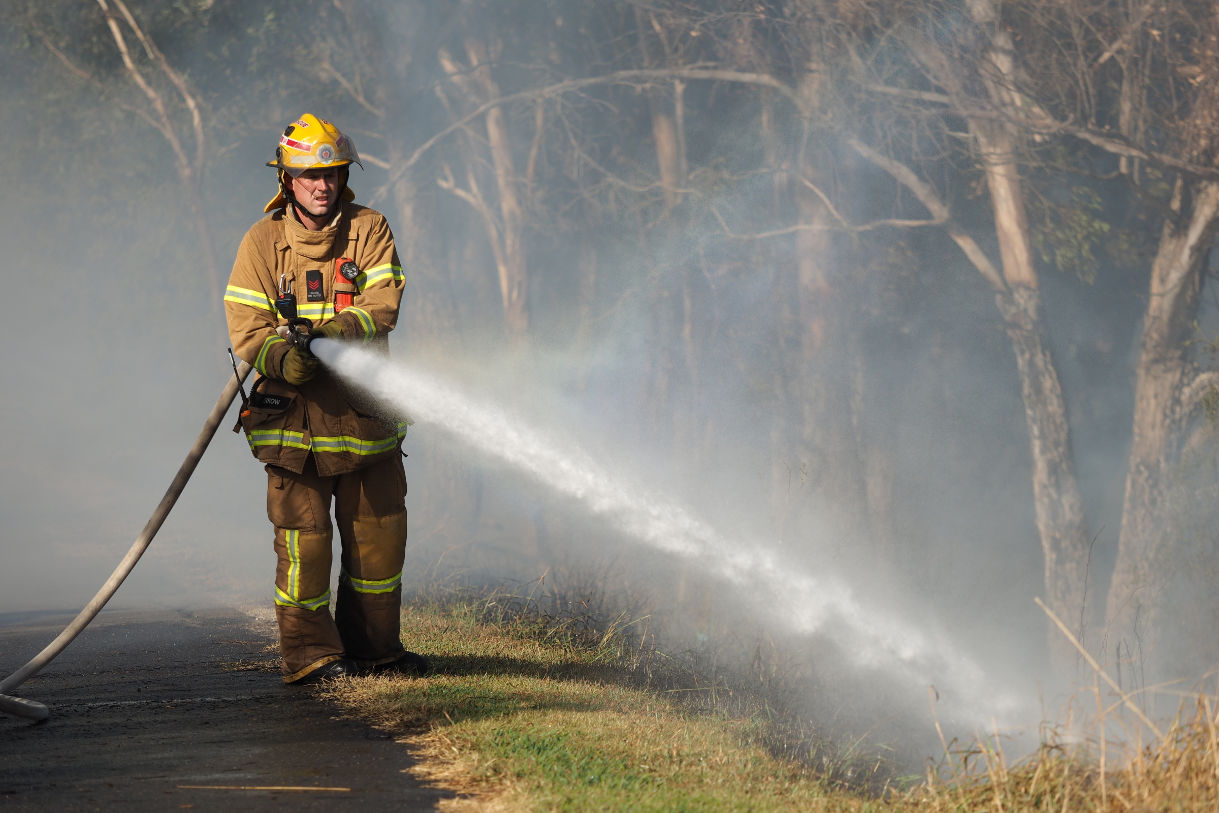 Firefighter spraying water on a bush fire in a suburban area of Knox City in Melbourne east