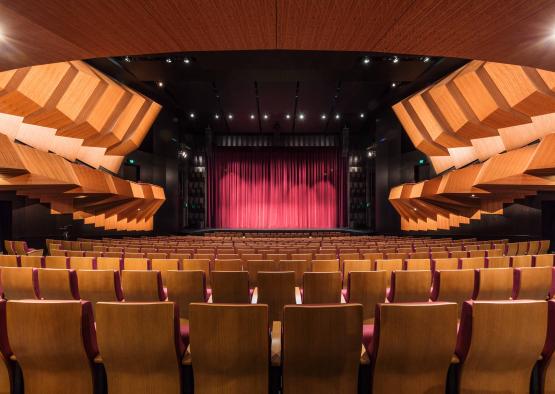 a theater with red curtains and wooden seats