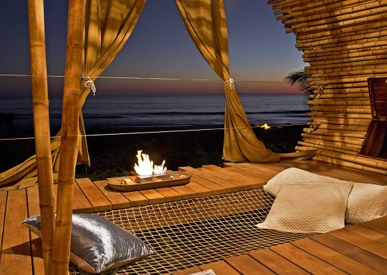 a fire pit on a deck with pillows and a blanket on it