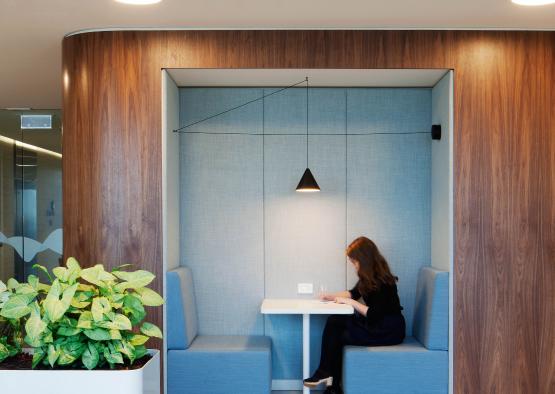 a woman sitting at a table in a room with blue booths