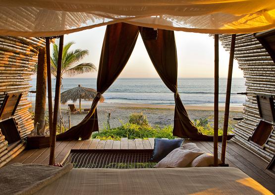a room with a bed and hammocks on the beach