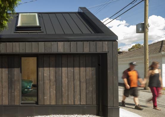 a man walking past a small wooden building