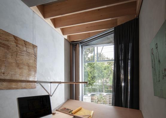 a desk with a computer and a lamp in a room with a window