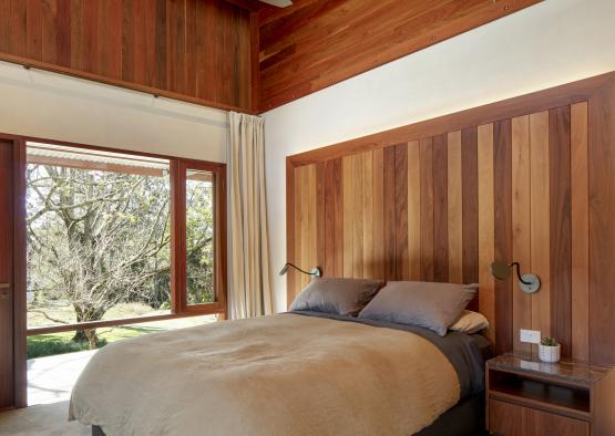 a bedroom with wood paneled headboard and ceiling fan