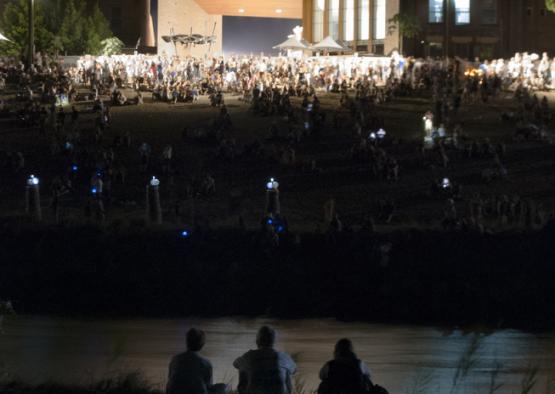 people sitting on the ground watching a concert