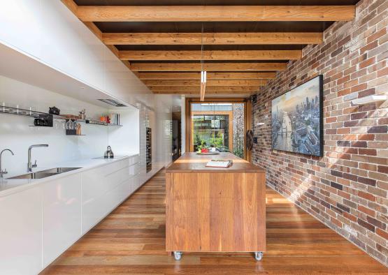 a kitchen with a wood island and brick wall