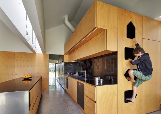 a boy climbing up a wall in a kitchen