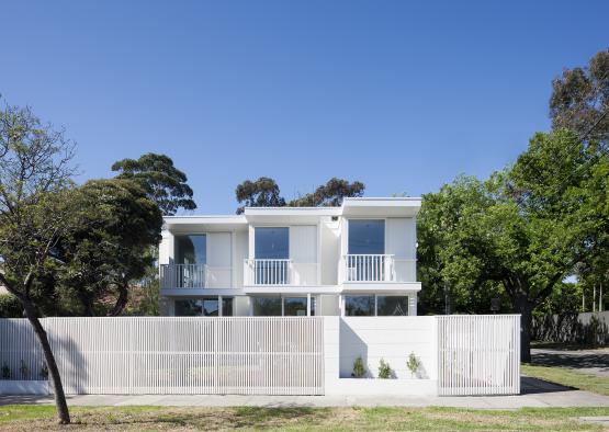 a white house with a fence and trees