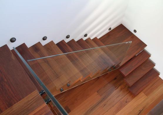 a glass stair case with wood floor and white walls