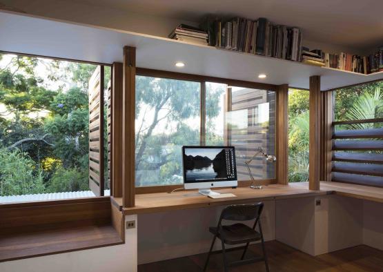 a desk with a computer and a chair in front of a window