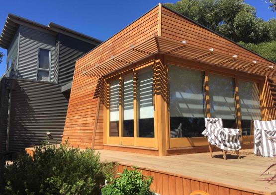 a wooden house with a chair on a deck