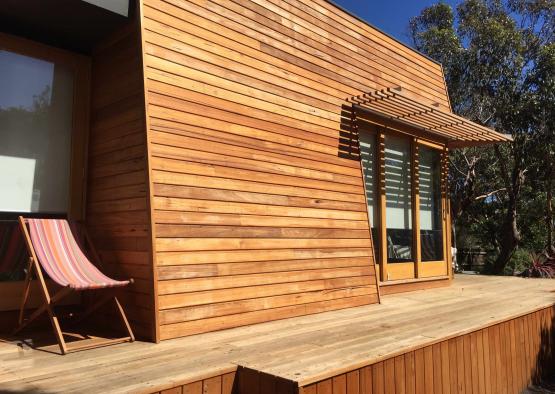 a wood house with a deck and a chair