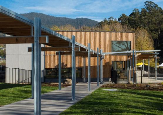 a walkway with metal poles and a building with trees in the background