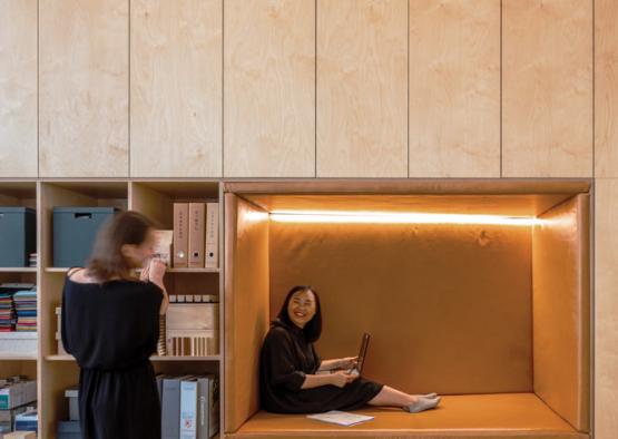 two women sitting on a bench in a room with books