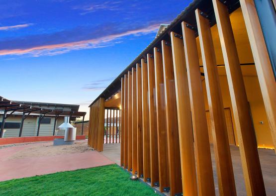 a wooden fence with a green lawn and a building