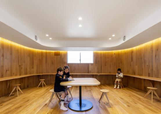 a group of kids sitting at a table in a room with wood walls