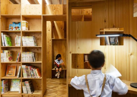 a boy standing in front of a bookcase