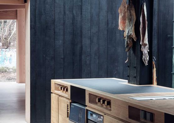 a kitchen with a black wall and wood cabinets