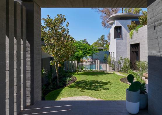 a patio with a potted plant and a yard with trees and a pool