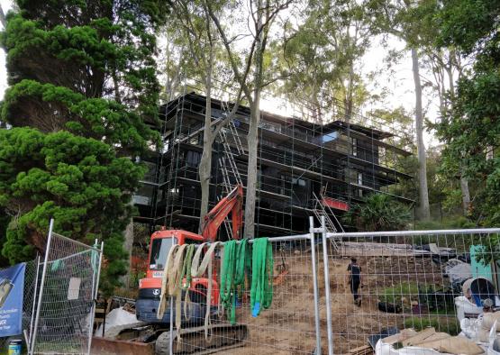 a building under construction with a crane and trees