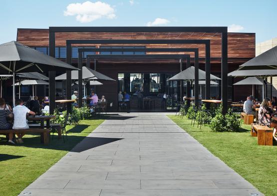 a walkway with tables and umbrellas in front of a building