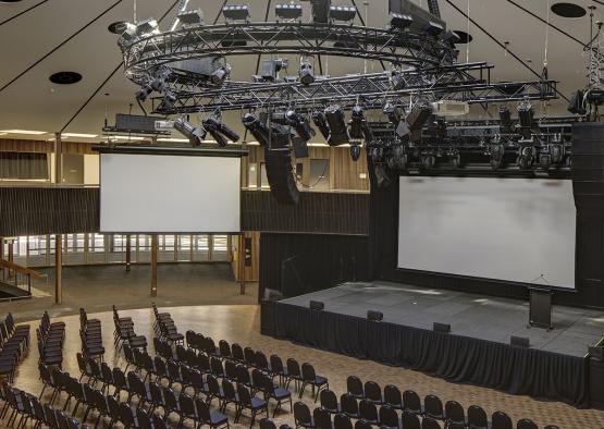 a large auditorium with a large screen and chairs