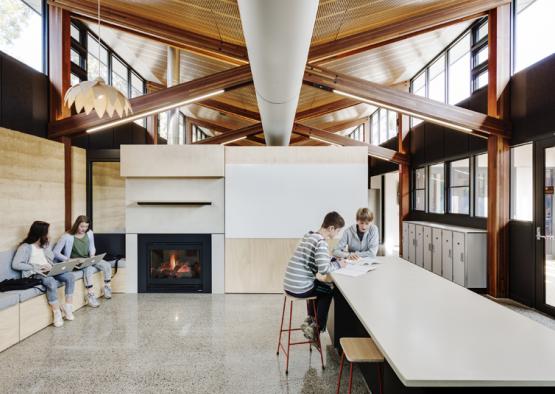 a group of people sitting at a table in a room with a fireplace