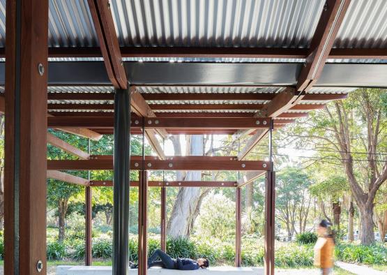 a person lying on a bench under a metal roof