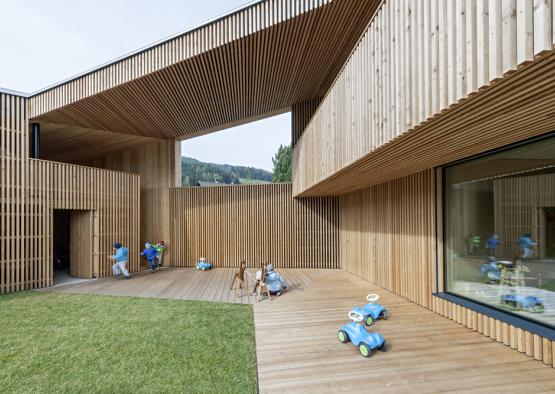 a wooden building with a wooden deck and a green lawn