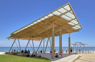 a beach covered area with people sitting on grass and a swing