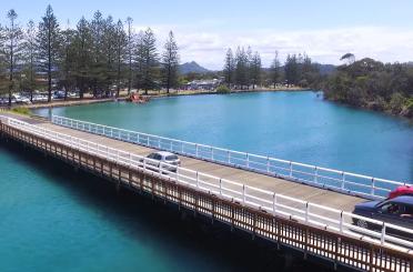 a bridge over water with cars and trees