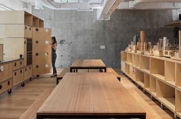 a woman standing in a room with wooden tables