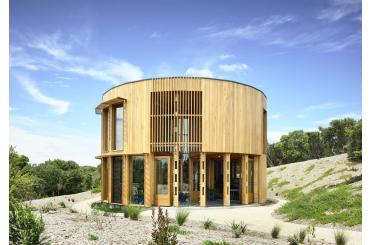 a circular building with a grassy hill and trees